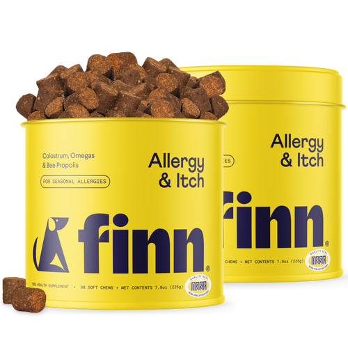 Two yellow cylindrical containers of Finn Allergy & Itch dog supplement with brown chew treats scattered around and on top