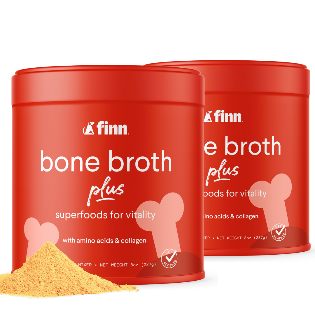 Two red cylindrical containers of Finn bone broth plus powder with white text and bone graphics, yellow powder visible