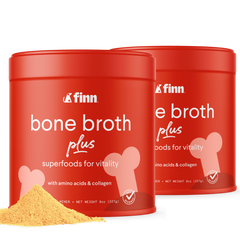 Two red cylindrical containers of Finn bone broth plus powder with white text and bone graphics, yellow powder visible