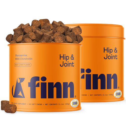 Two orange containers of Finn Hip & Joint dog supplements with brown chews scattered around and spilling from one container