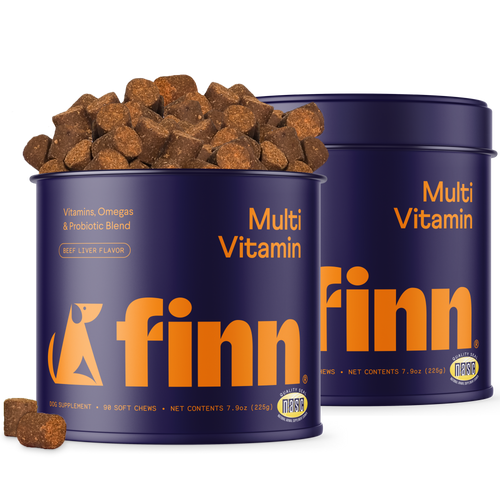 Two purple cylindrical containers of Finn Multi Vitamin dog supplements with orange text, beef liver flavored soft chews scattered around