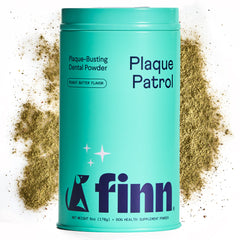 Turquoise canister of Finn Plaque Patrol dental powder for dogs with peanut butter flavor, surrounded by spilled green powder