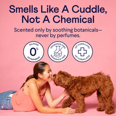 Woman in pink top cuddling brown fluffy dog on pink background with product claims about fragrance-free, sulfate-free formulation