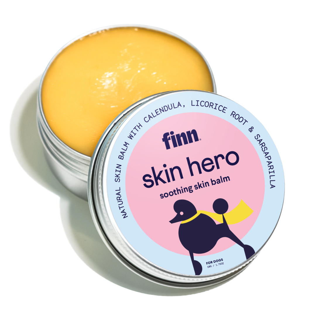 Open tin of yellow skin balm with pink and blue label featuring black dog silhouette, labeled "finn skin hero soothing skin balm"
