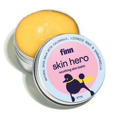 Open tin of yellow skin balm with pink and blue label featuring black dog silhouette, labeled "finn skin hero soothing skin balm"