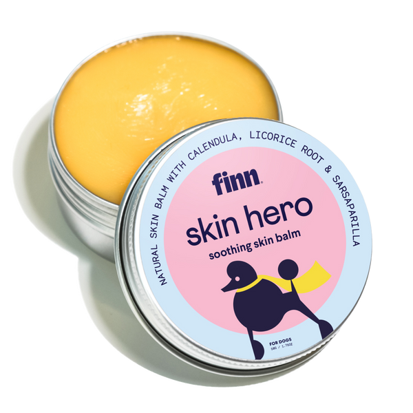Open tin of yellow skin balm with pink and blue label featuring black dog silhouette, labeled "finn skin hero soothing skin balm"