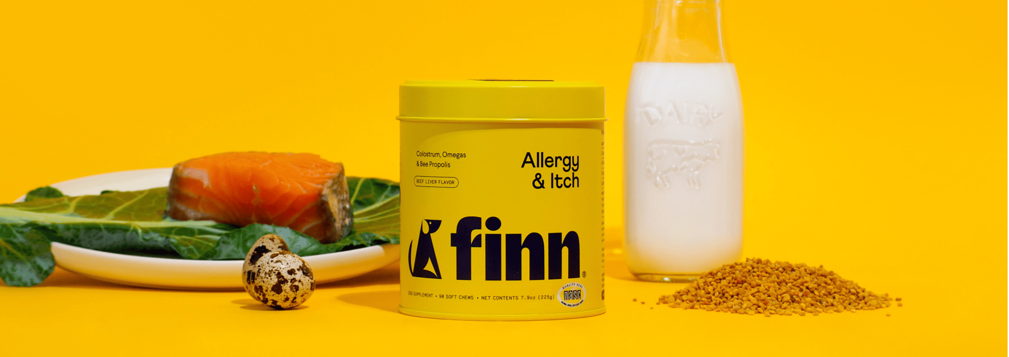 Yellow Finn pet supplement container for allergies and itching, surrounded by salmon, greens, quail egg, milk glass, and bee pollen on yellow background.