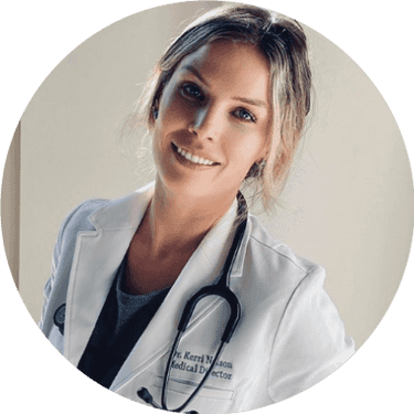 Smiling female healthcare professional with blonde hair wearing white medical coat and stethoscope against neutral background