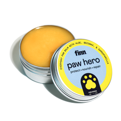 Open tin of yellow paw balm with blue and yellow label reading "finn. paw hero protect • nourish • repair" with paw print logo