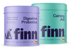 Two cylindrical pet supplement containers - purple "Digestive Probiotics" and teal "Calming Aid" from Finn brand for dogs