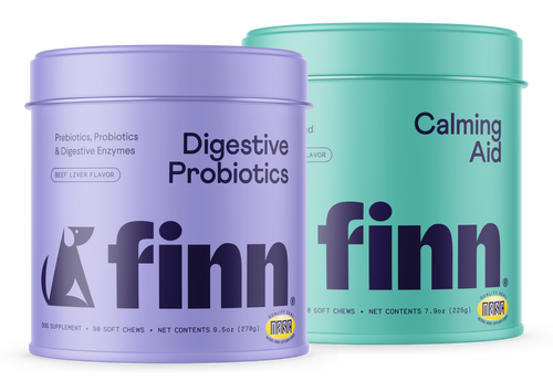 Two cylindrical pet supplement containers - purple "Digestive Probiotics" and teal "Calming Aid" from Finn brand for dogs